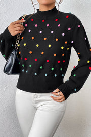 Black blouson sweater with colorful pom-pom embellishments and mock neck.
