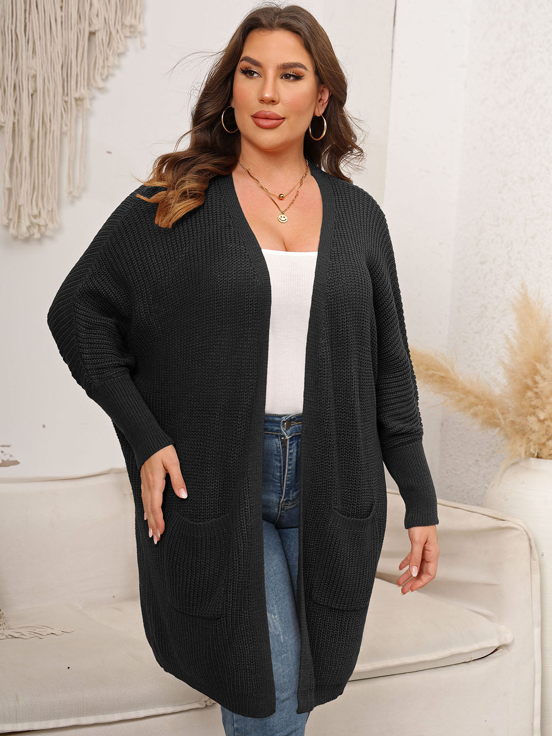 Black oversized ribbed knit duster cardigan with pockets and long sleeves.