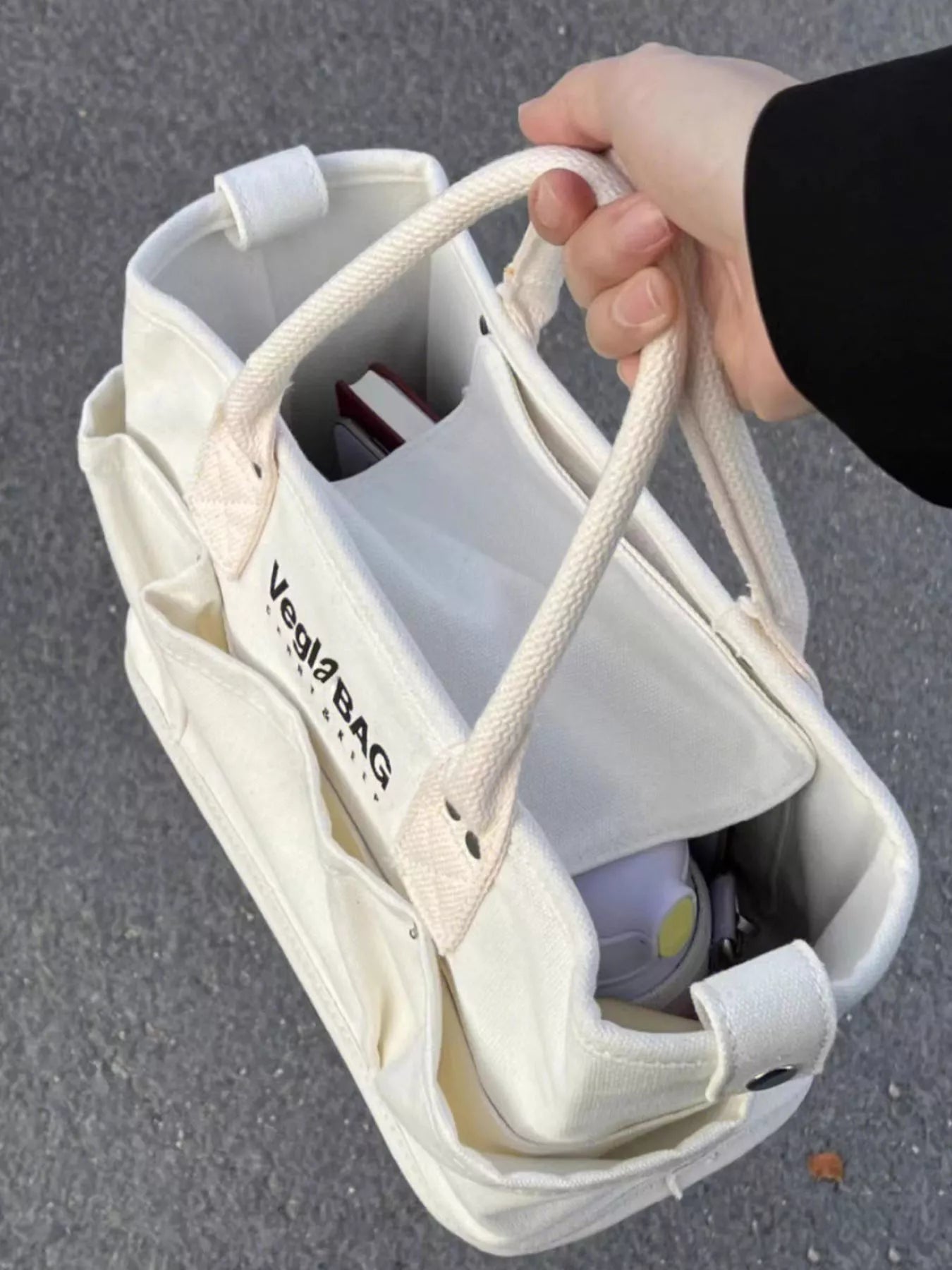 Beige canvas shopper bag with multiple exterior pockets and rope handles.