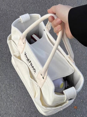Beige canvas shopper bag with multiple exterior pockets and rope handles.