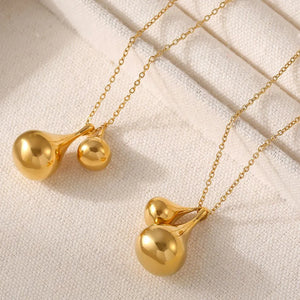 Gold pendant necklace with polished, sculptural teardrop charms on a delicate chain.