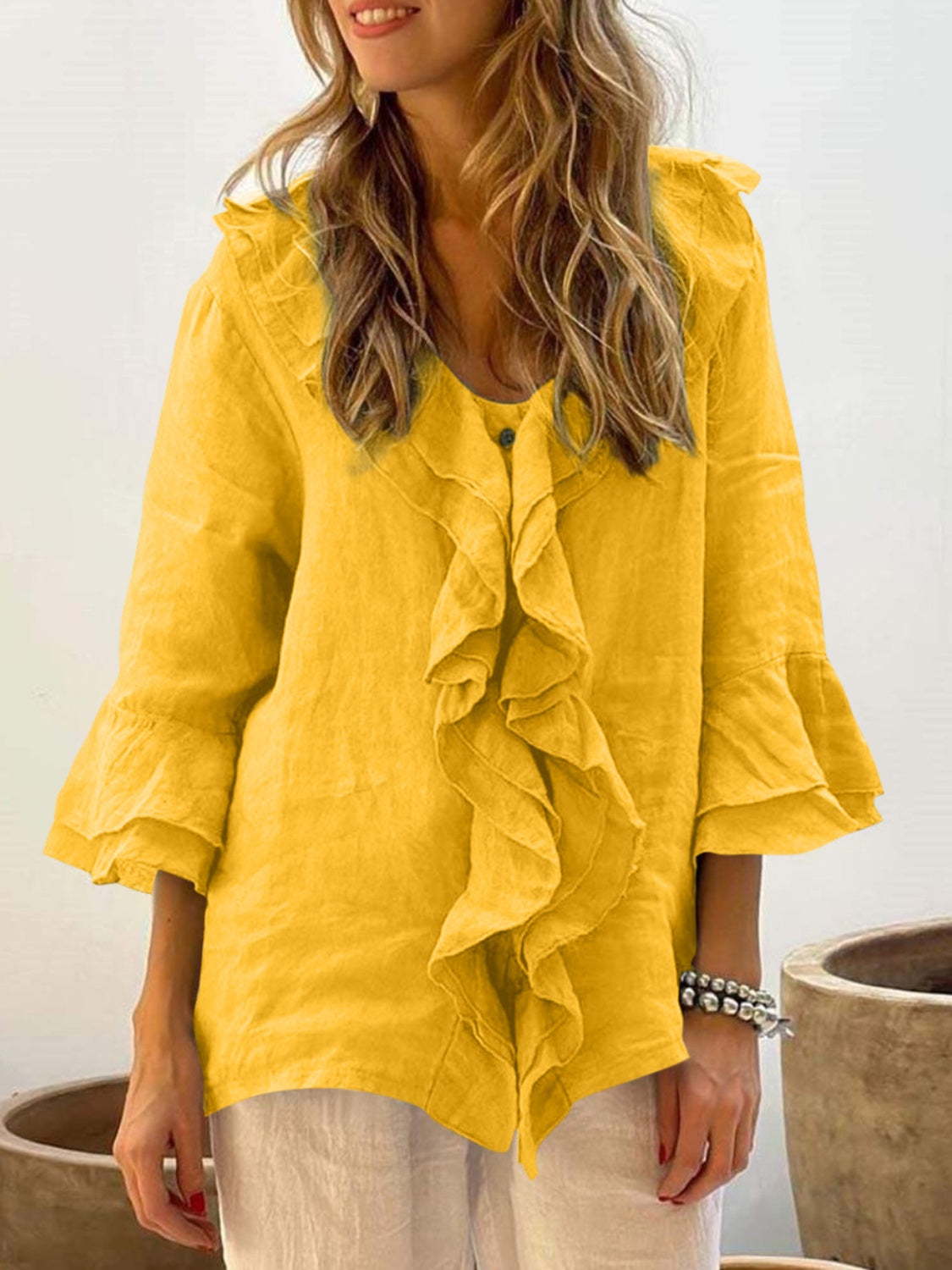 Yellow linen blouse with ruffled front and flared sleeves.