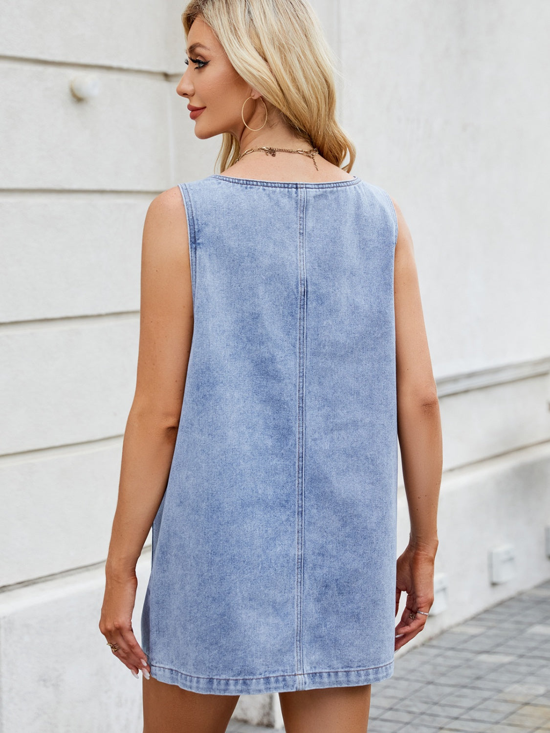Light blue denim pinafore mini dress with a sleeveless design and a straight hem.