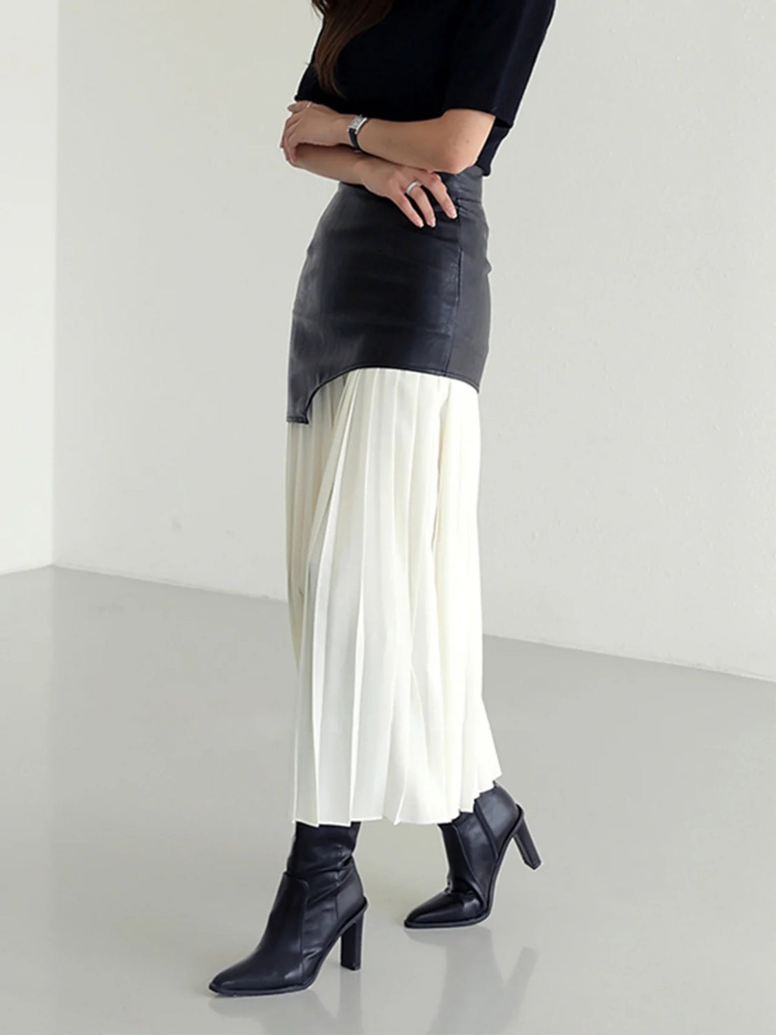 Black asymmetric leather midi skirt with white pleated chiffon overlay.