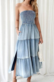 Light blue denim strapless tiered maxi dress with smocked bodice and side slits.