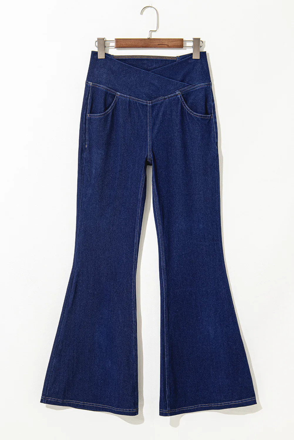Medium wash denim flare trousers with asymmetric crossover waist and front pockets.