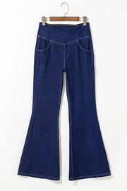 Medium wash denim flare trousers with asymmetric crossover waist and front pockets.