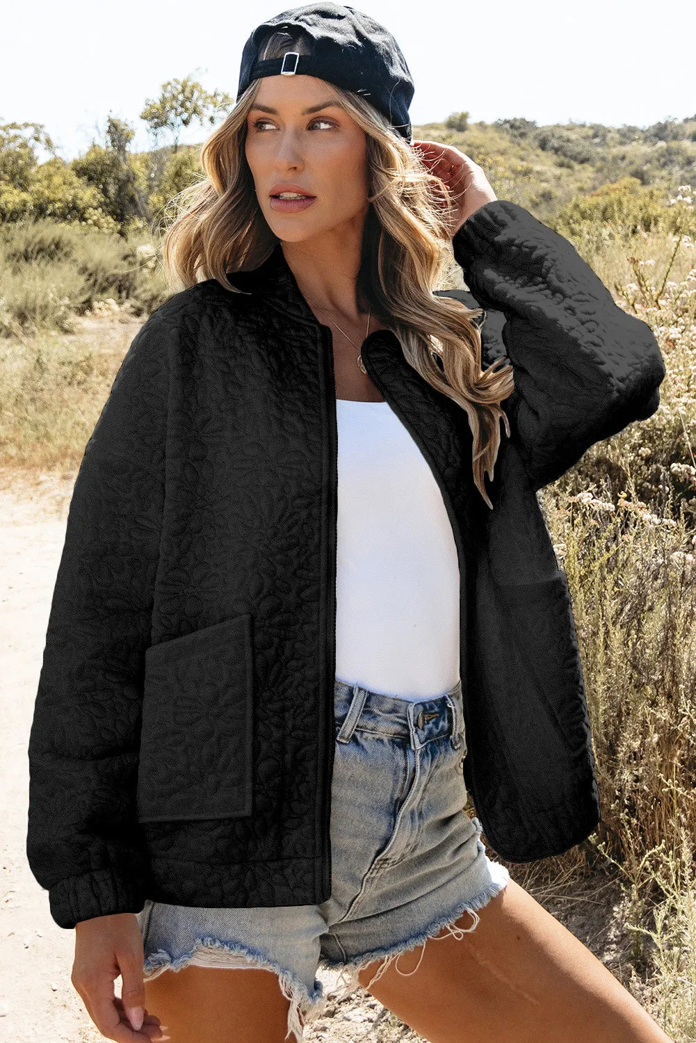 Black quilted bomber jacket with floral pattern and front pockets.