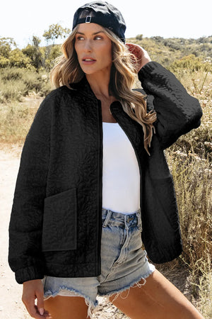 Black quilted bomber jacket with floral pattern and front pockets.