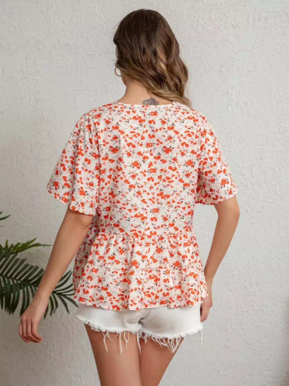 Vibrant floral peplum blouse with ruffle sleeves and a tiered hem.