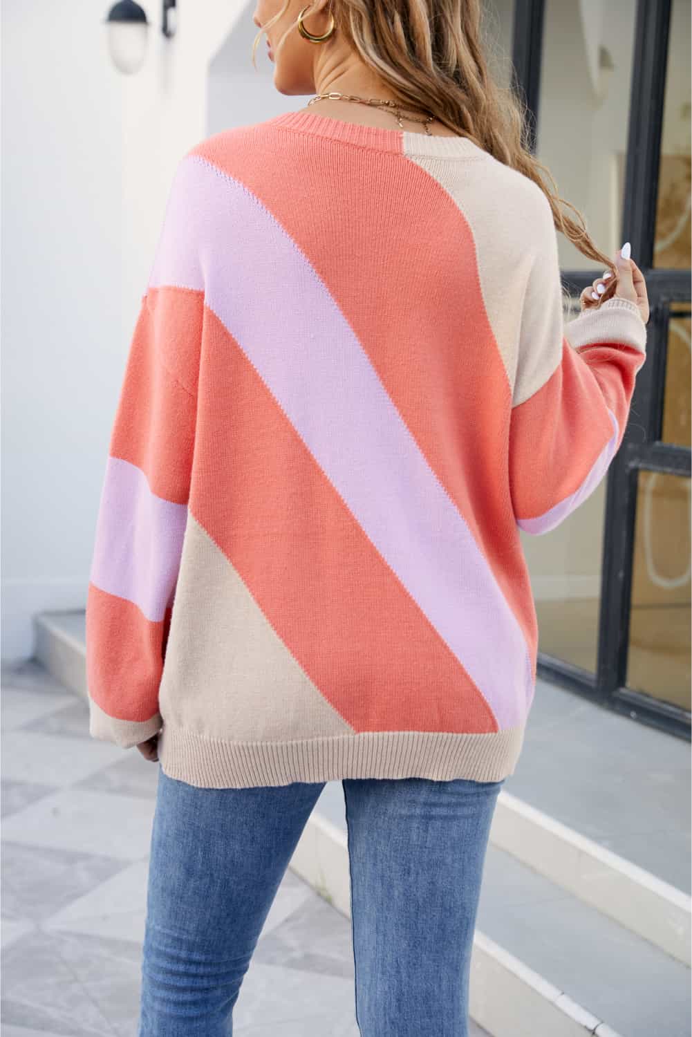 Diagonal colorblock knit sweater in orange and coral with a crew neck and long sleeves.