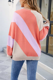 Diagonal colorblock knit sweater in orange and coral with a crew neck and long sleeves.