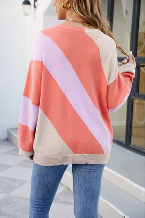 Diagonal colorblock knit sweater in orange and coral with a crew neck and long sleeves.