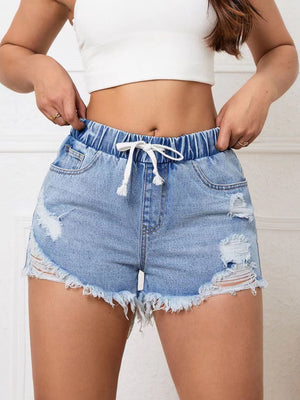 Light wash denim shorts with elastic waist, drawstring, and distressed details.