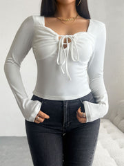 White ruched bustier long sleeve top with tie-front detail and square neckline.