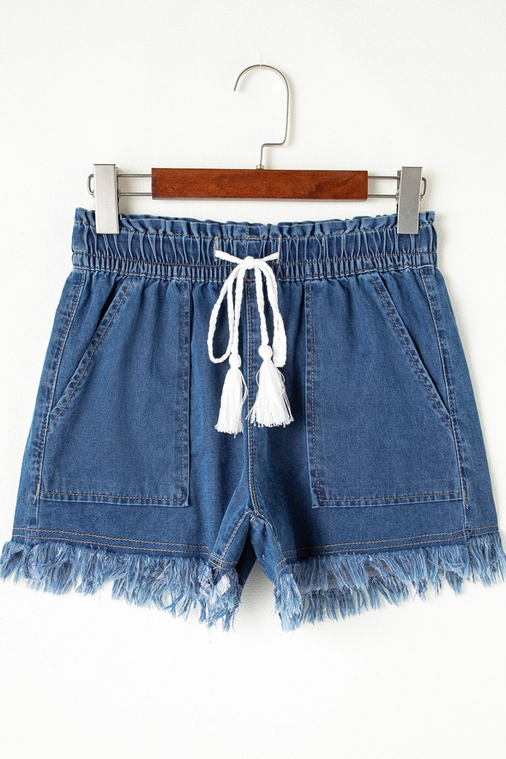 Navy denim drawstring shorts with frayed hem and tassel detail