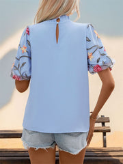 Light blue blouse with floral embroidered organza puff sleeves and mock neck.