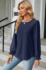 Dark blue textured puff sleeve blouse with ruffled cuffs.