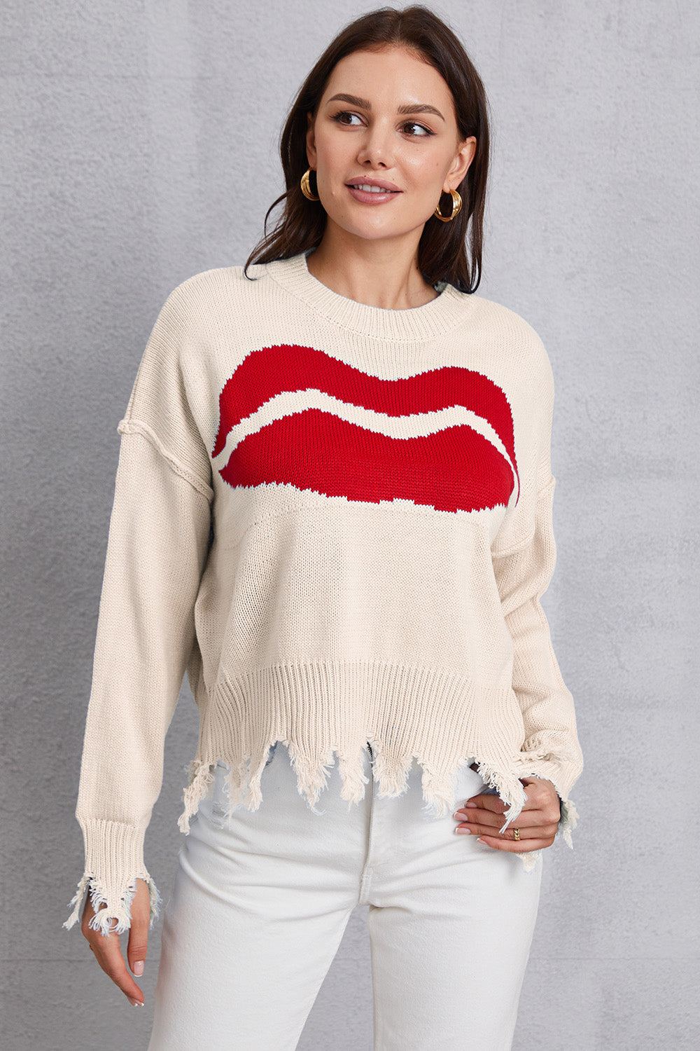 Cream knit sweater with red kiss graphic and distressed hem.