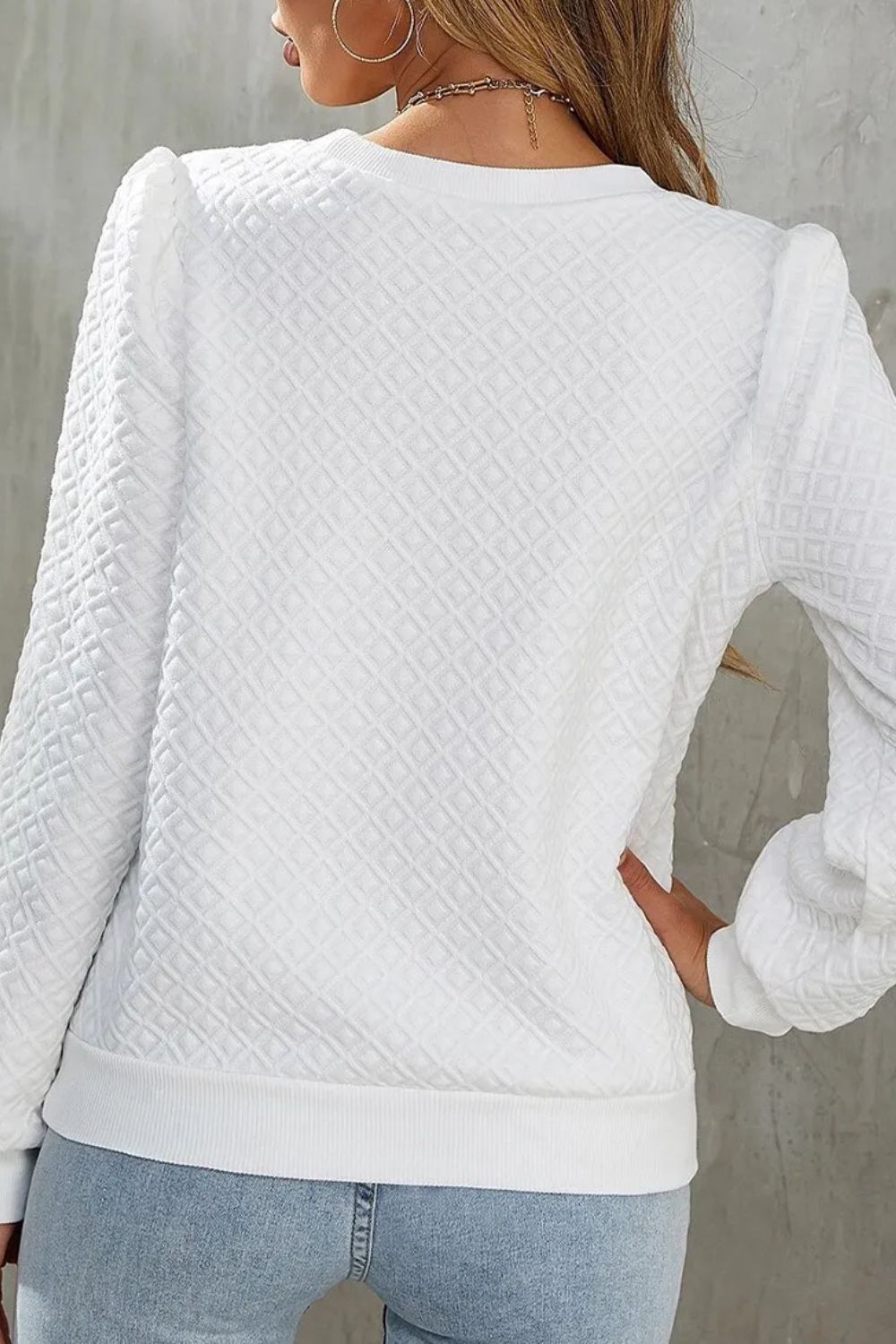 White crewneck pullover with textured diamond pattern and puff sleeves.