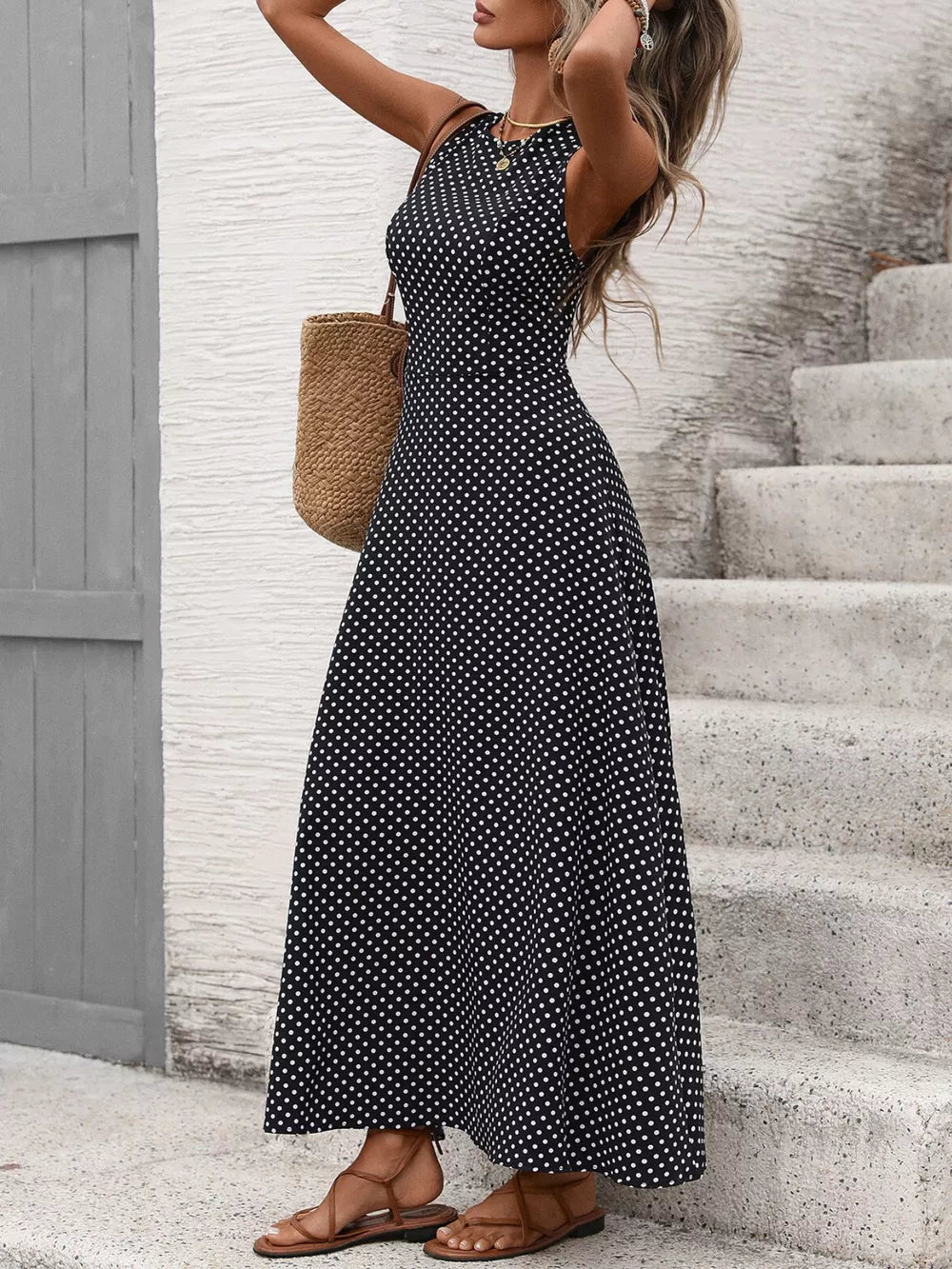 Black polka dot maxi dress with flattering silhouette, sleeveless, round neck, flowy skirt.