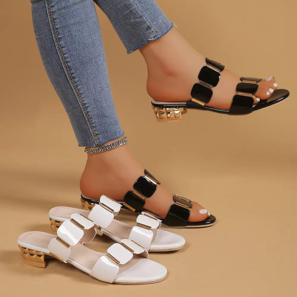 Glossy black and white block heel sandals with gold accents, featuring a slip-on design.