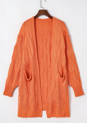 Burnt Coral cable knit open-front cardigan with pockets and textured sleeves.