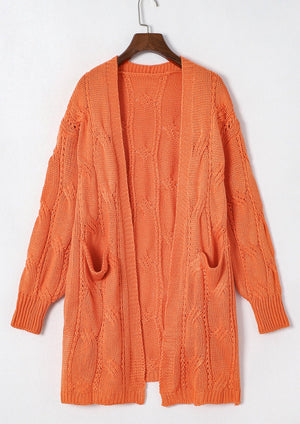 Burnt Coral cable knit open-front cardigan with pockets and textured sleeves.