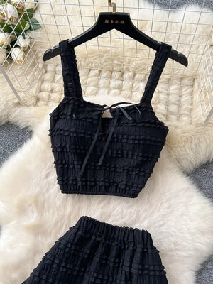 Black ruched crop top with ribbon tie and matching ruffled shorts.