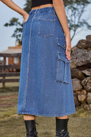 Denim midi skirt in medium blue with cargo pockets, buttoned flap pockets, and a slit.