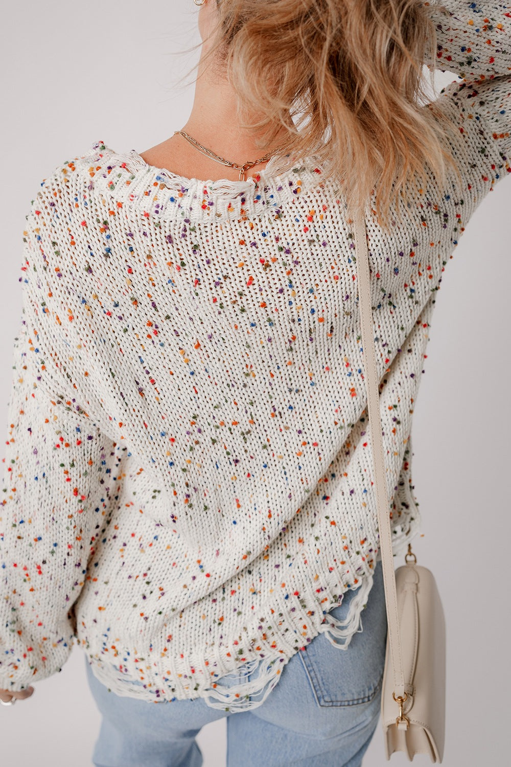 Confetti knit sweater in white with colorful flecks, distressed hem, and frayed neckline.