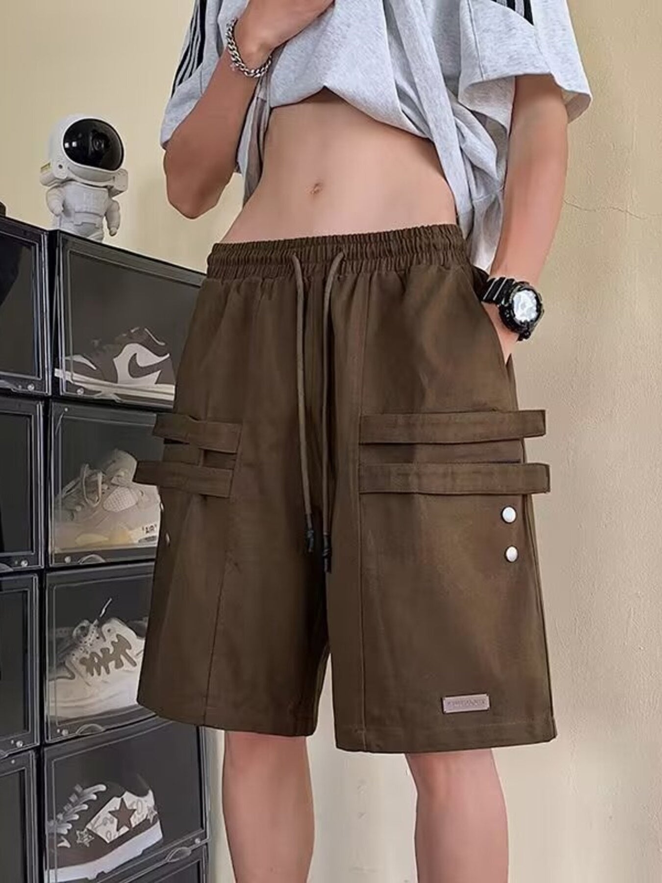 Brown cargo shorts with drawstring and double strap pocket details.