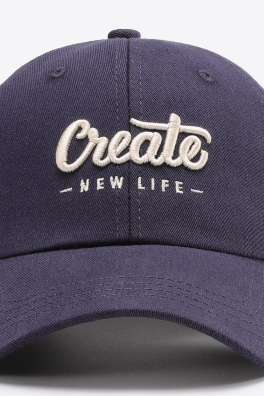 Navy baseball cap with embroidered "Create New Life" text detail