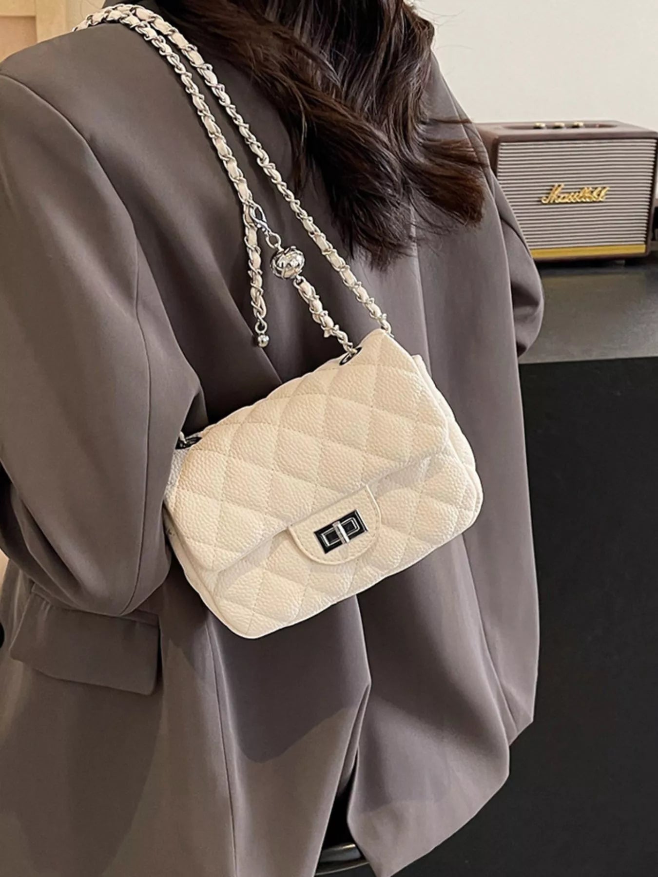 Quilted chain crossbody clutch in rice white with a silver clasp and chain strap.