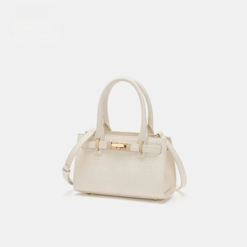 Off-white crocodile-embossed mini tote handbag with gold hardware and top handles.