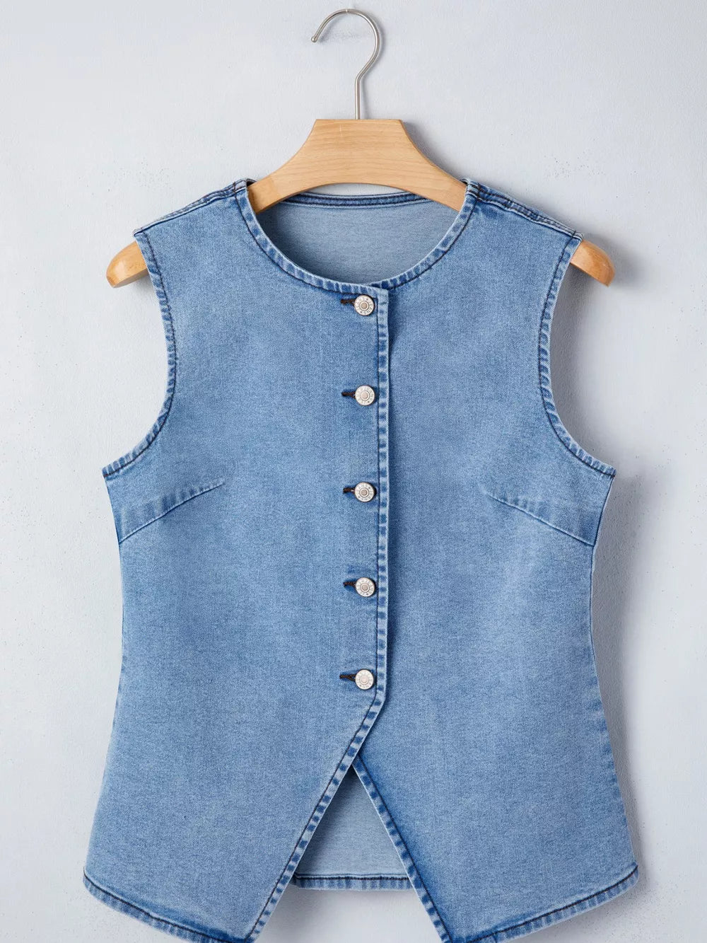 Light wash denim vest with button front and a slit detail.