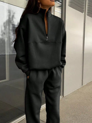 Black half zip sweatshirt and matching sweatpants set with a mock neck.