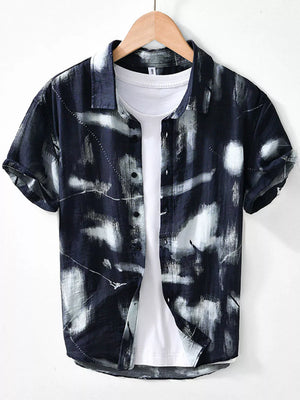 Men's black abstract print short sleeve button-down shirt layered over a white tee