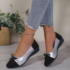 Black and silver bow-embellished slip-on flats with a low wedge heel.