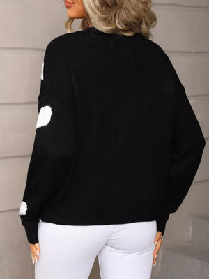 Black knit cardigan with white heart pattern, button-up front, crew neck, long sleeves.