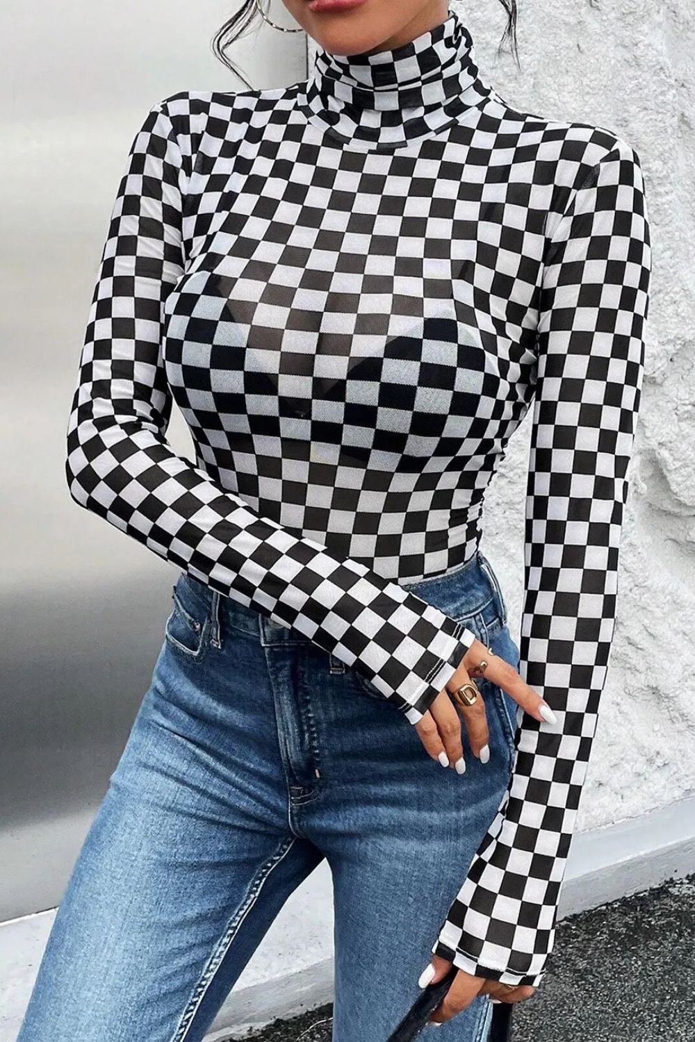 Checkerboard mesh turtleneck bodysuit with long sleeves, styled with jeans.