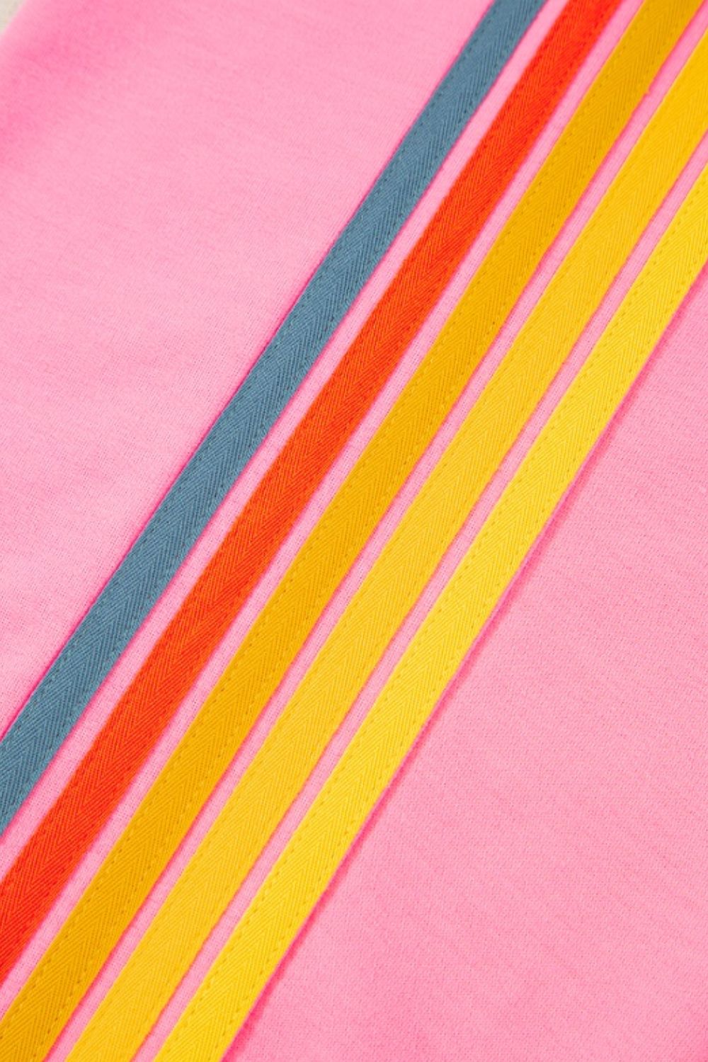 Pink track pants with rainbow stripe detail in blue, orange, and yellow.