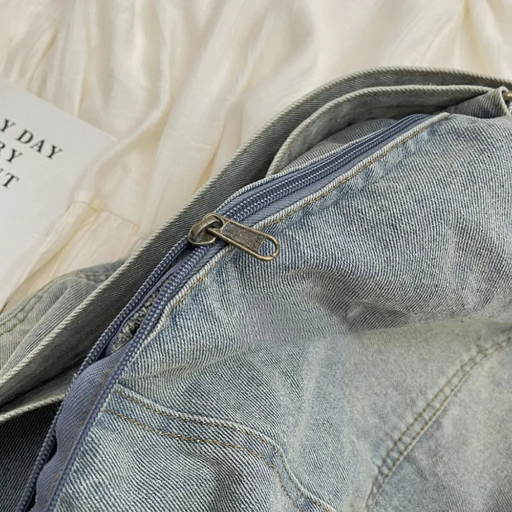 Light washed denim hobo bag with a zippered closure and antique brass hardware.