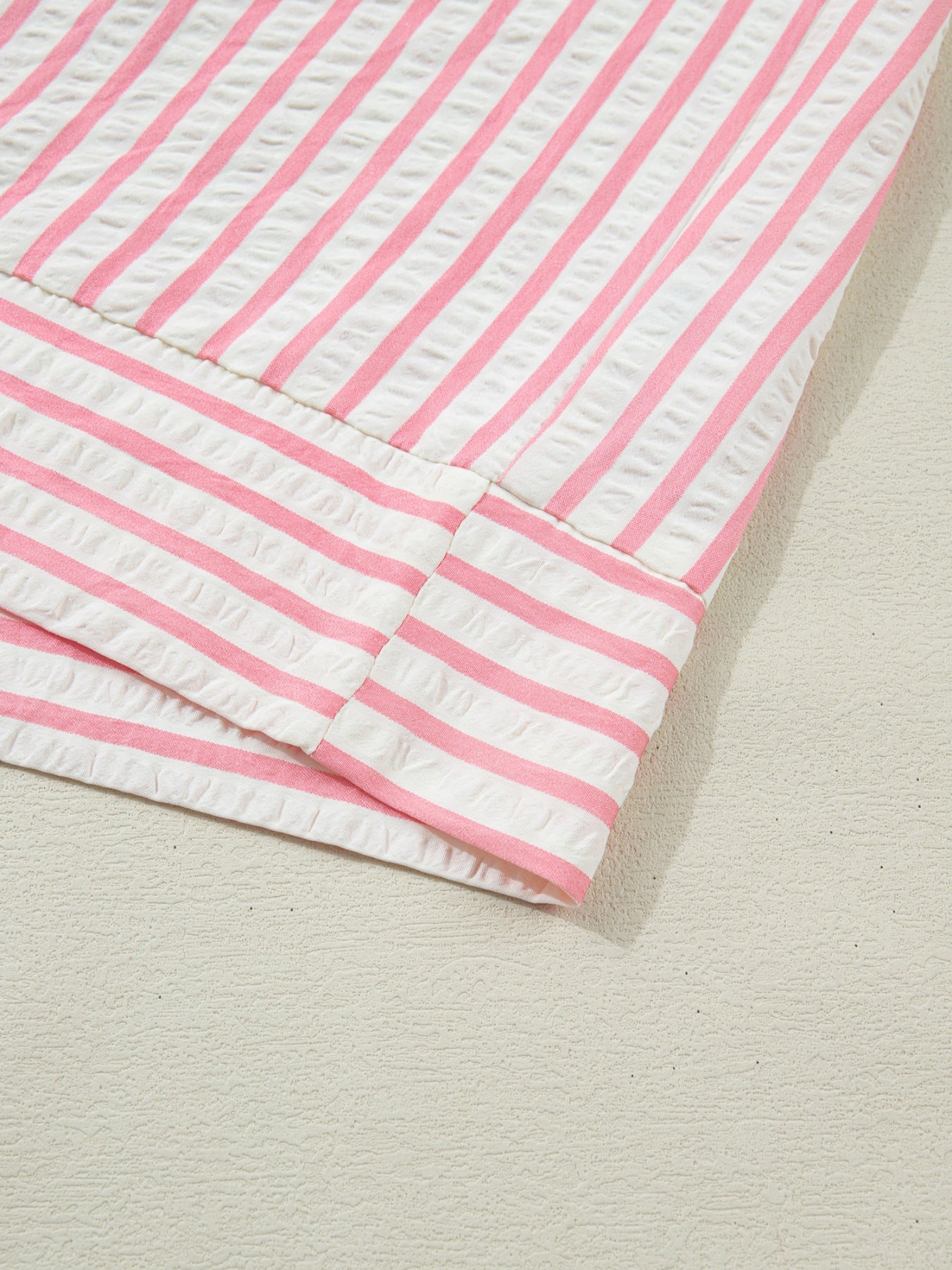 Pink and white striped seersucker blouse with textured fabric detail.