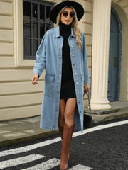 Light blue oversized denim duster jacket with button front and chest pockets, worn open over a black dress.