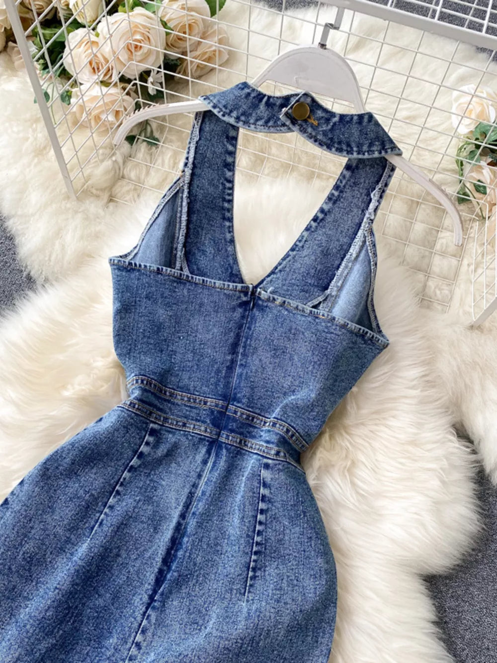 Blue denim halter neck jumpsuit with button detail at collar and wide legs.