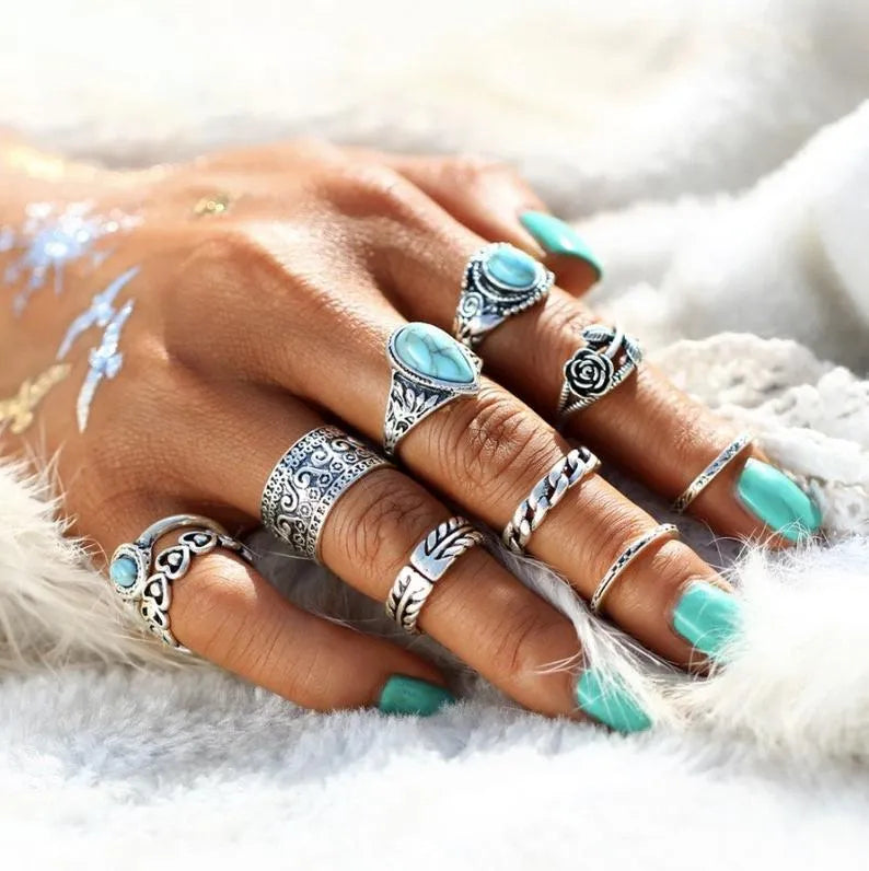Bohemian silver rings with turquoise stones and intricate patterns on a hand.