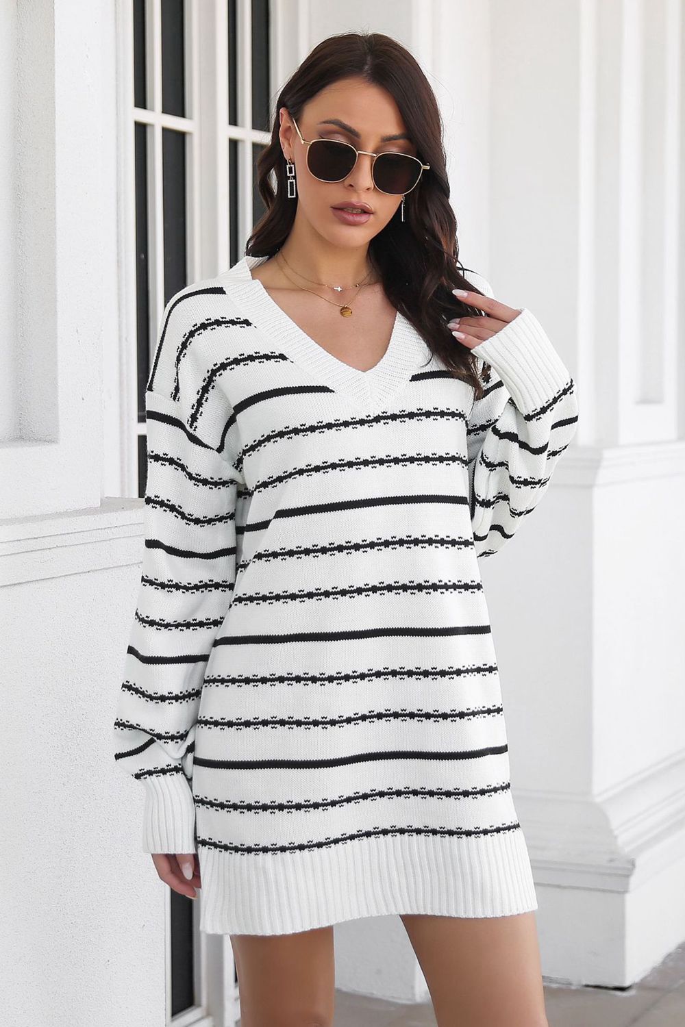 Textured stripe knit mini dress in white and black with a V-neck and long sleeves.