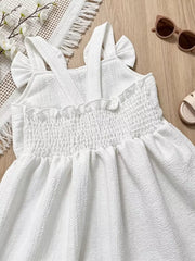 White baby dress with smocked bodice, ruffle trim, and bowknot straps.