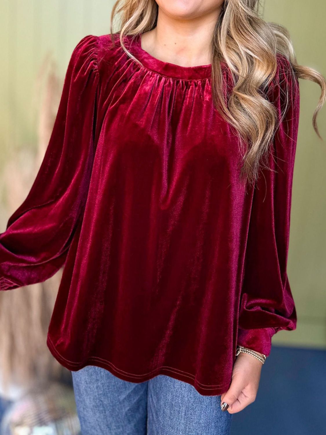 Burgundy velvet blouse with ruched neckline and long puff sleeves.